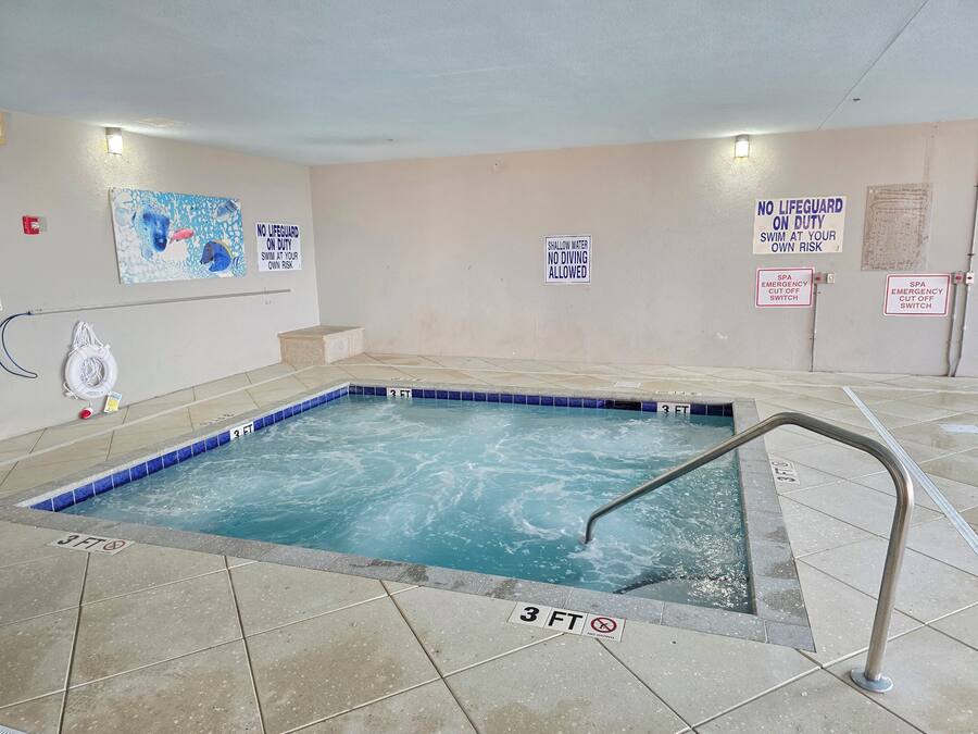 A small indoor pool with a 3-foot depth limit, surrounded by tiled flooring and walls with safety signs.