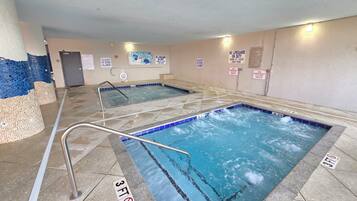 Una piscina interior con agua cristalina, pisos de baldosas y señales de seguridad.