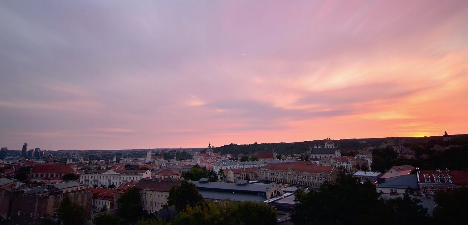 A cityscape at sunset with historic buildings and a prominent church.