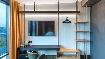 A modern hotel room with a desk, chair, and a TV mounted on the wall.