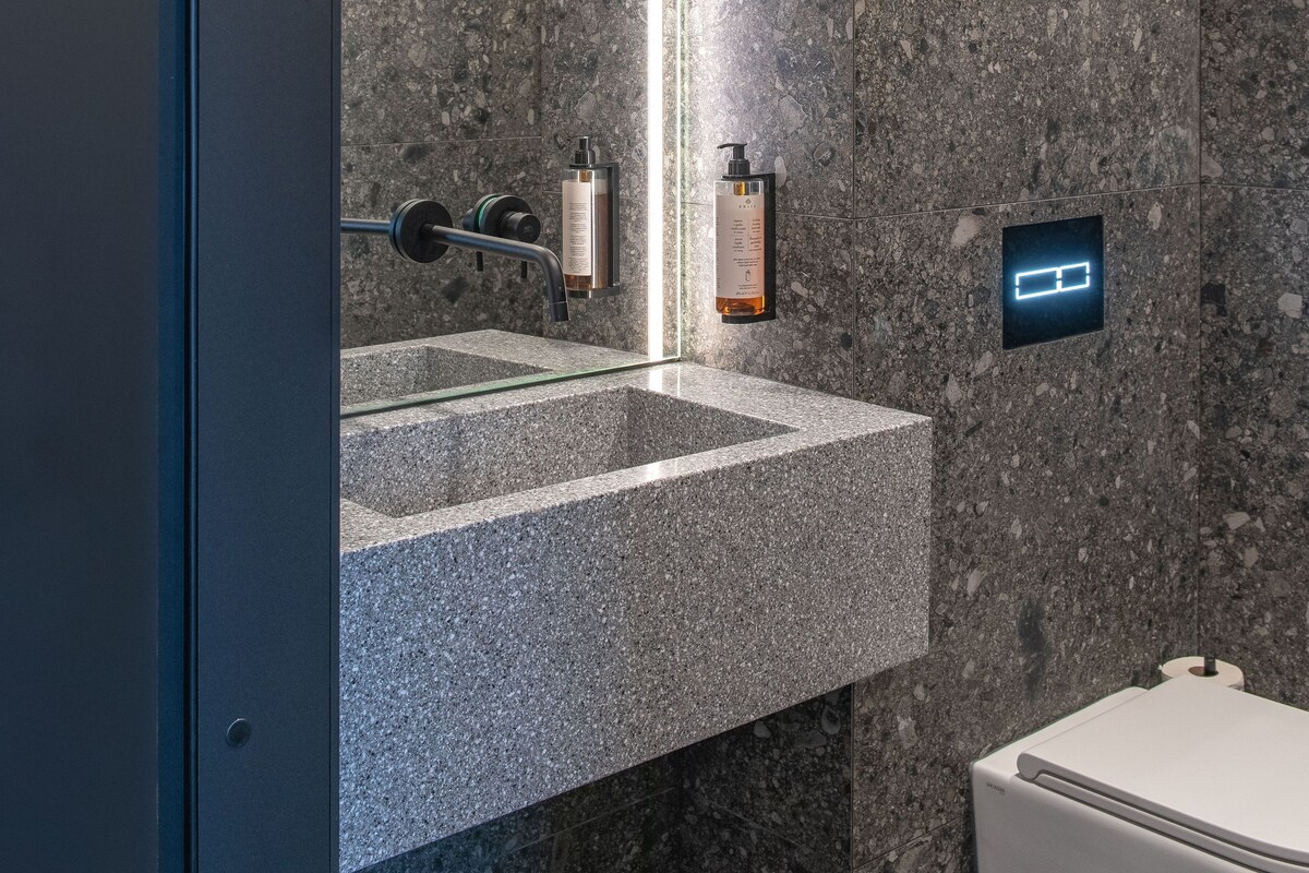 A bathroom with a granite countertop sink, a mirror, and a toilet.