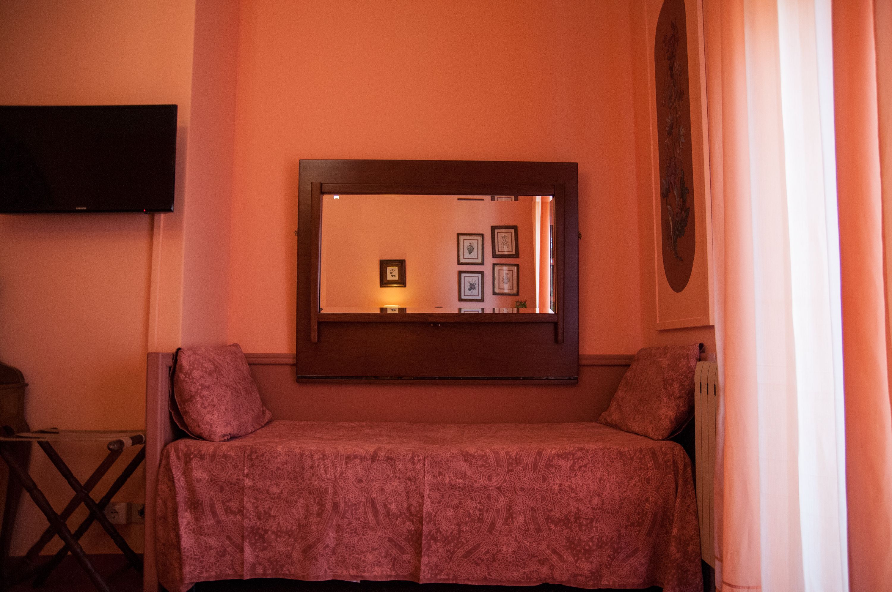 Een kamer met een bed, een tv aan de muur en wanddecoraties in lijsten.