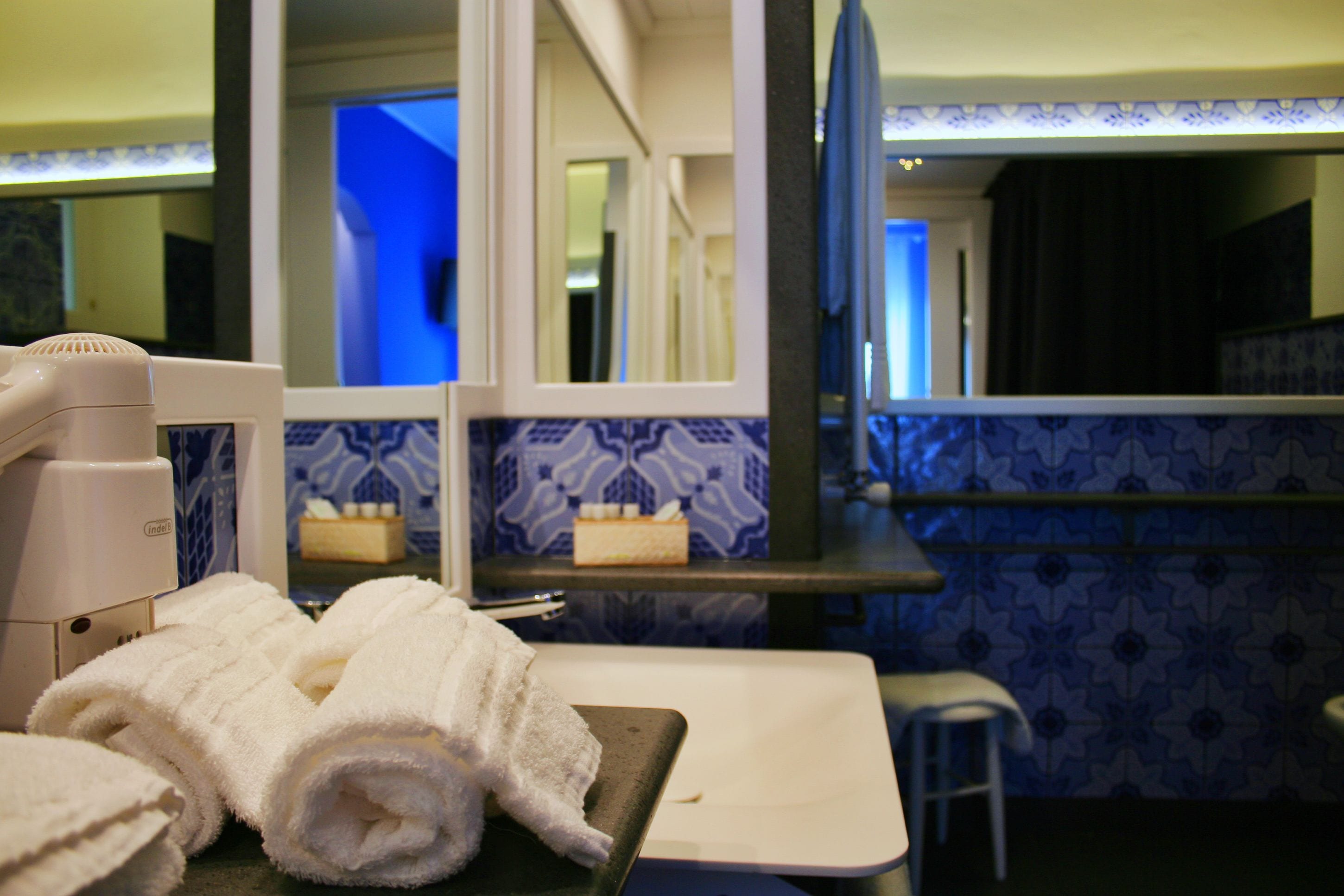 A bathroom with a sink, a mirror, and a towel stand.