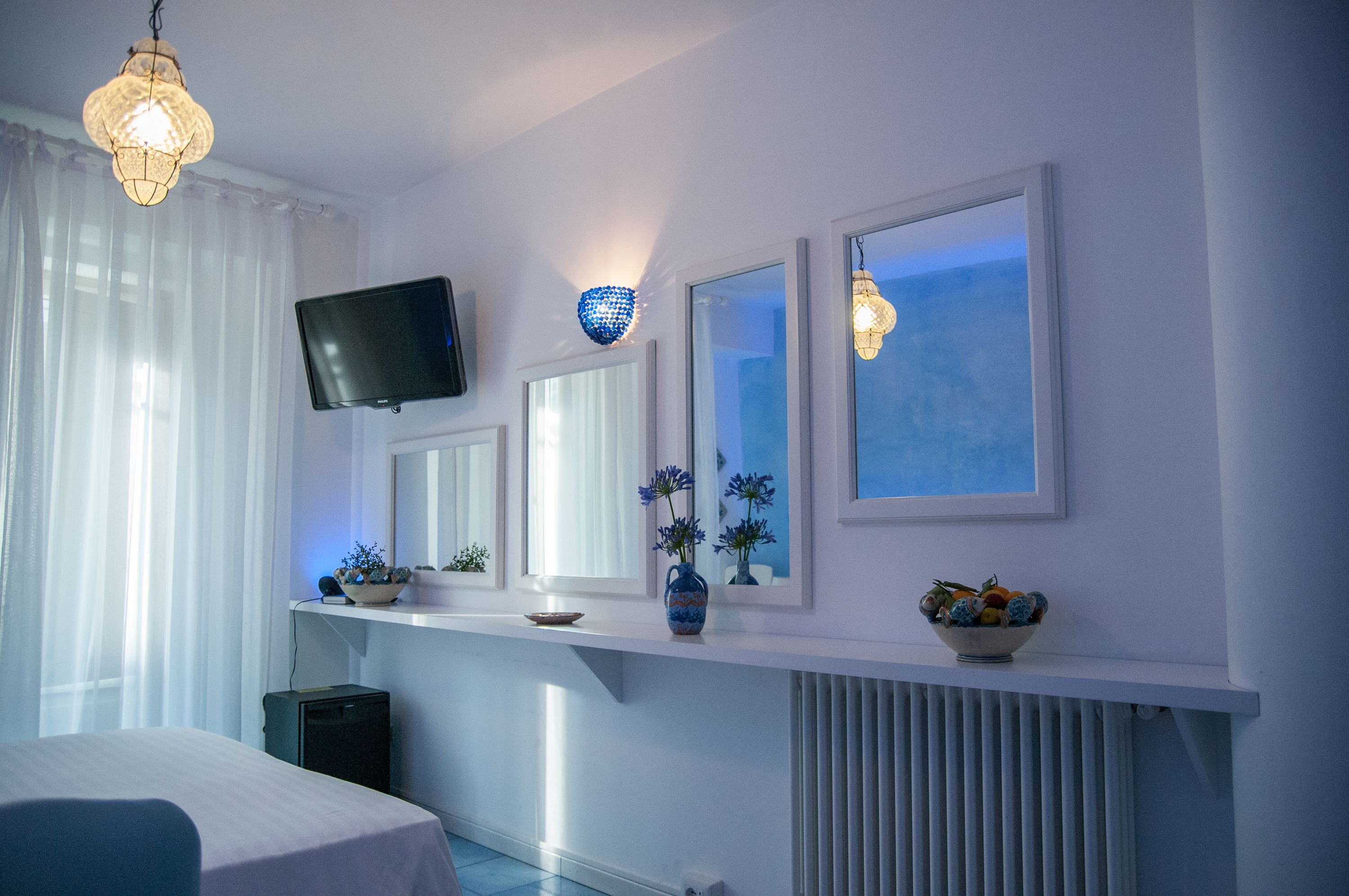 Une chambre d’hôtel avec un lit, une télévision, une étagère avec des objets décoratifs et une fenêtre donnant sur un paysage agréable.