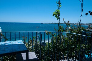 A balcony with a table and chairs overlooking the sea.