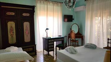 Una habitación de hotel con dos camas, un escritorio con silla, un televisor y un armario grande.