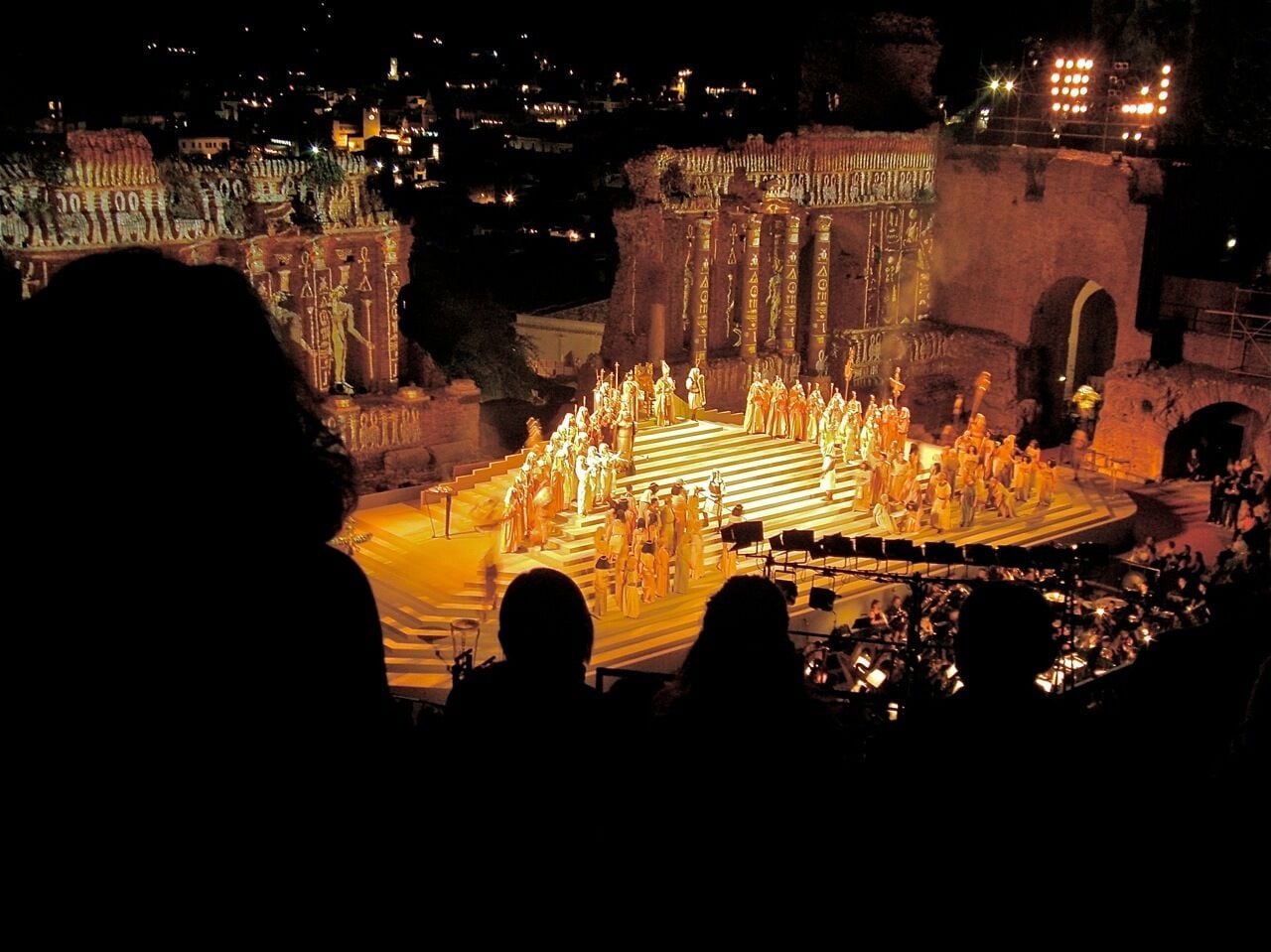 A nighttime outdoor performance with a group of people on a stage, surrounded by an audience.