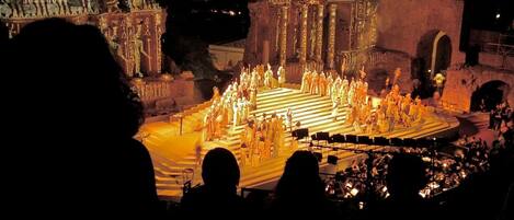 A nighttime outdoor performance with a group of people on a stage, surrounded by an audience.