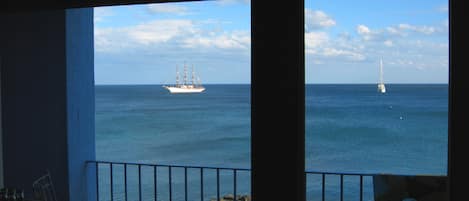Une vue depuis un balcon donnant sur la mer, où l’on aperçoit deux bateaux.