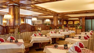 Un restaurant avec de nombreuses tables dressées pour le service, chacune étant recouverte d’une nappe blanche et agrémentée de serviettes rouges.
