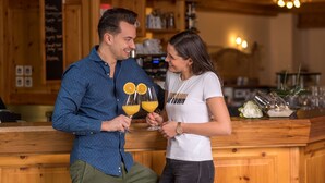 A wooden bar area with a counter, shelves with bottles, and a menu board. - Aktiv- & Wellnesshotel Zentral (Prato allo Stelvio)