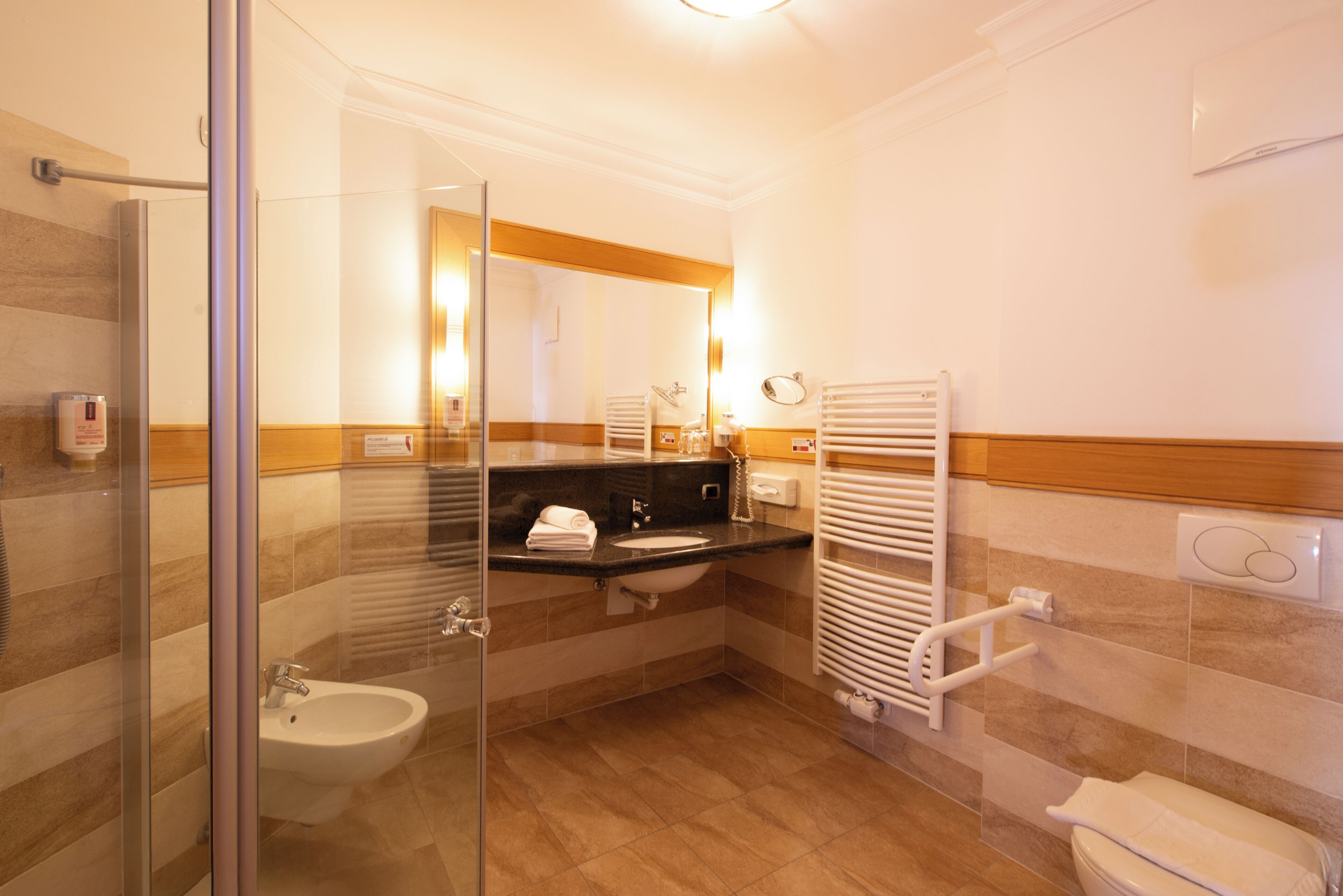 Ein modernes Badezimmer mit Duschkabine, Waschbecken, Toilette und Handtuchhalter.