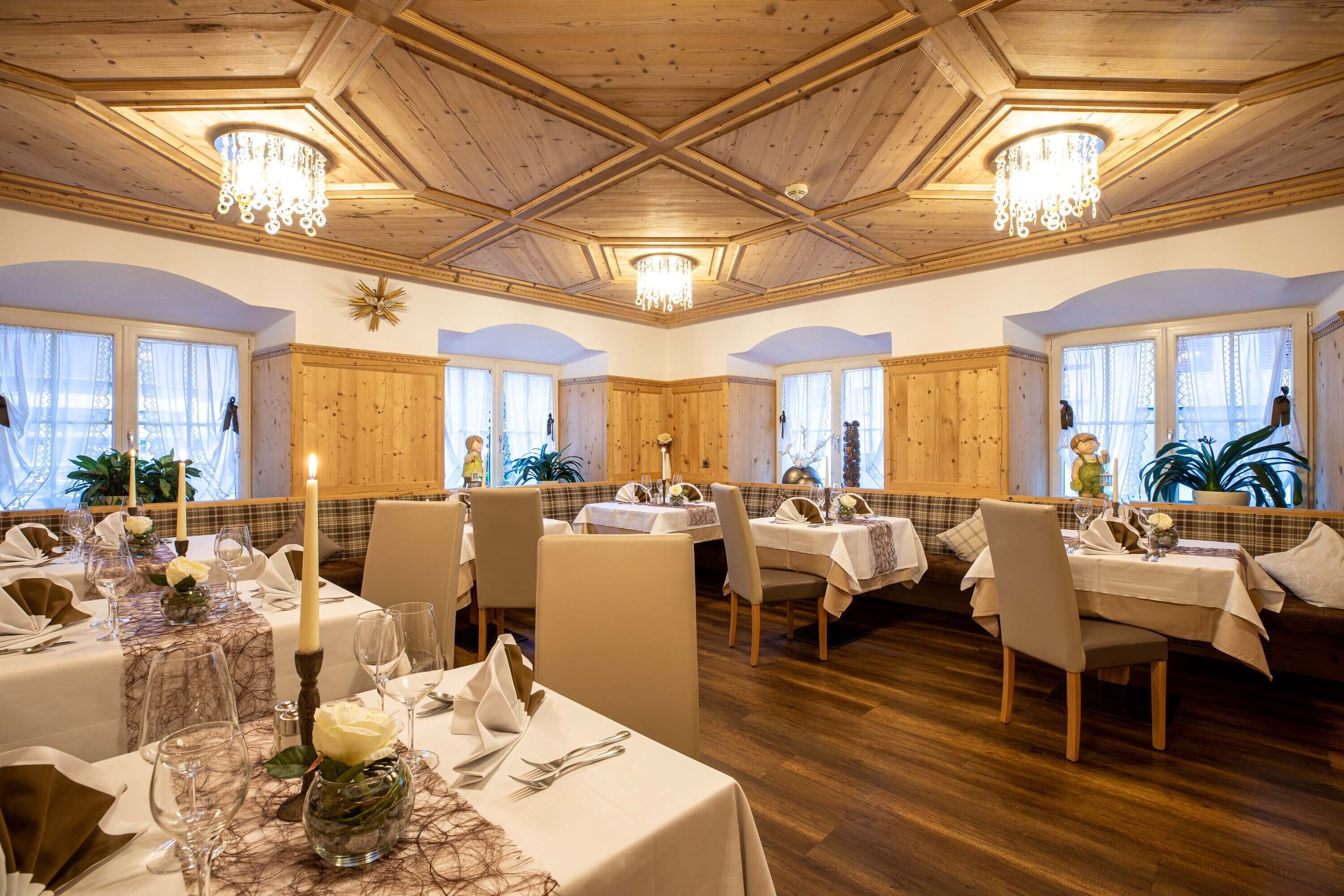 Un espace repas doté d’un plafond en bois, de lustres et de tables dressées pour le repas.