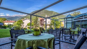An outdoor patio with round tables and chairs, a green tablecloth, and a potted plant. - Aktiv- & Wellnesshotel Zentral (Prato allo Stelvio)