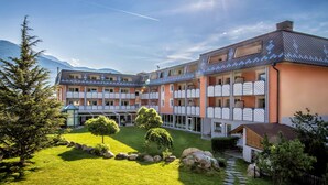 A hotel with a courtyard, multiple balconies, and a mountain backdrop. - Aktiv- & Wellnesshotel Zentral (Prato allo Stelvio)