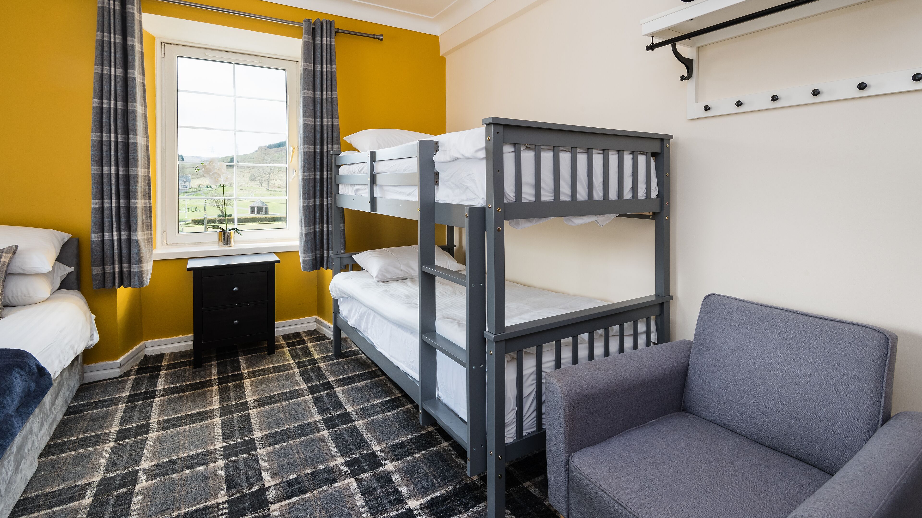 A bunk bed room with a checkered floor, a desk, and a chair.