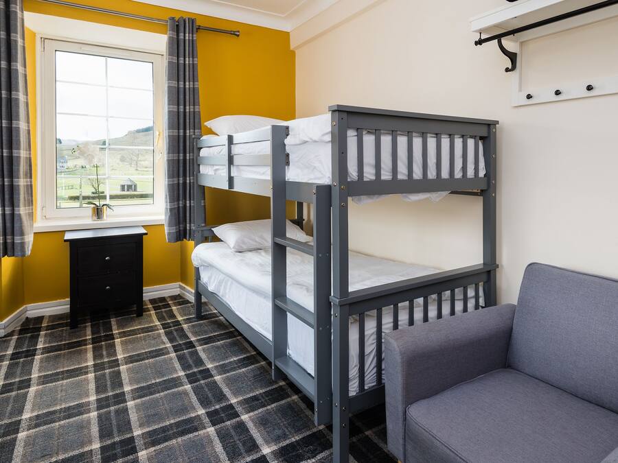 A bunk bed room with a checkered floor, a desk, and a chair.