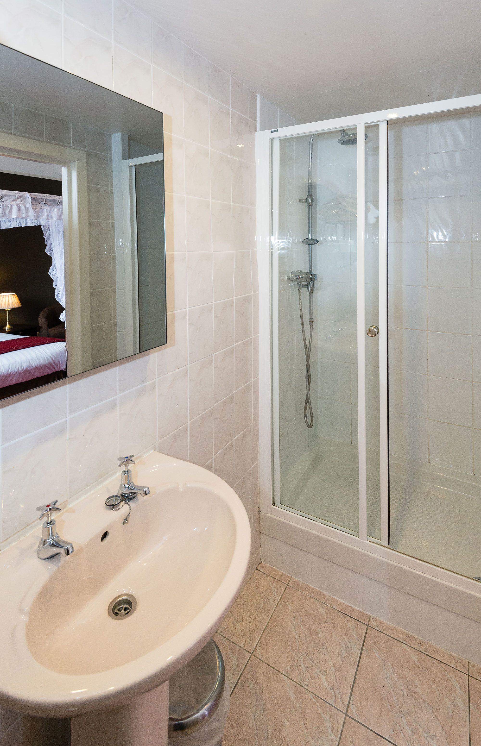 A bathroom with a white sink, a mirror, and a glass-enclosed shower.