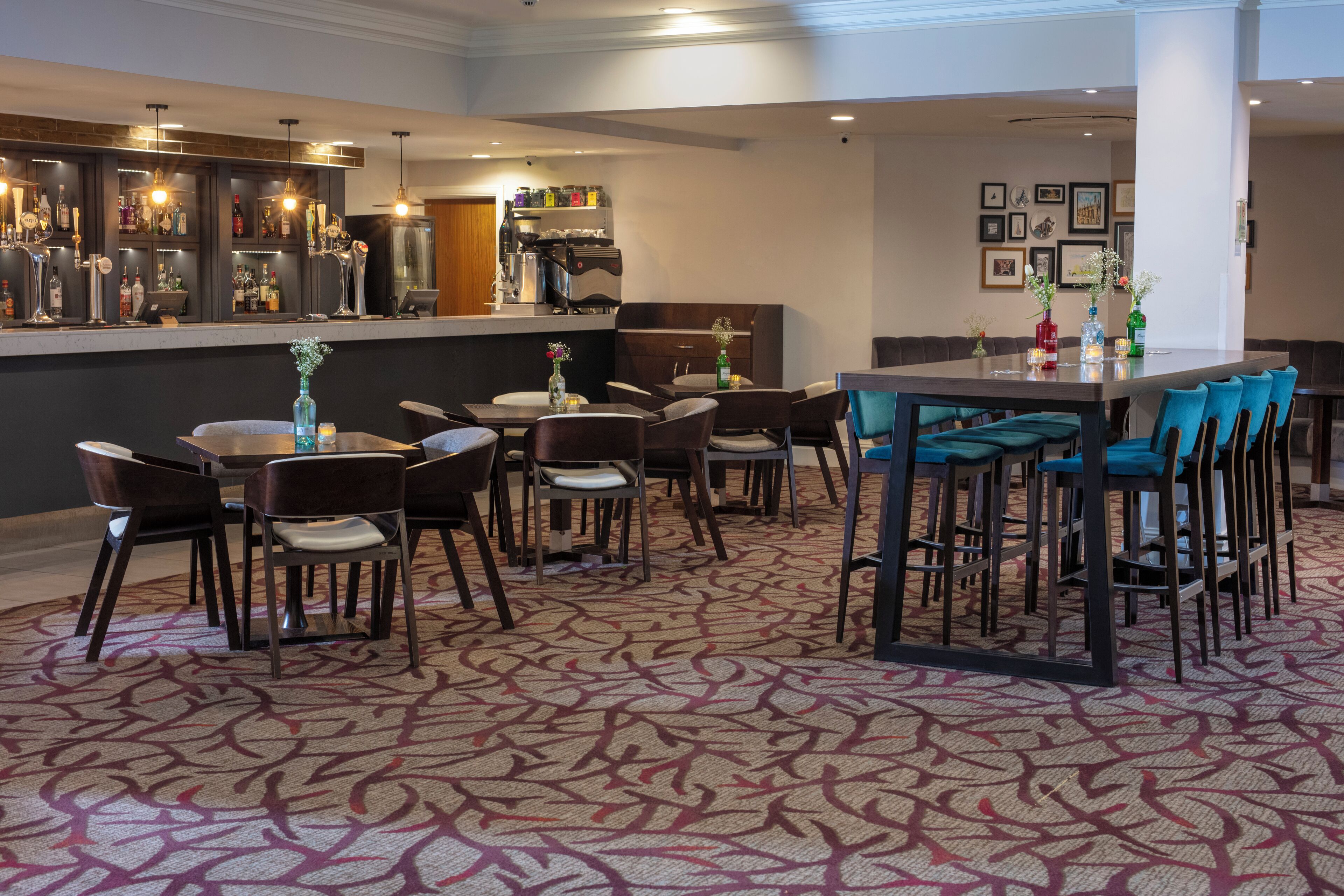 Un hall de hotel con zona de bar, distribución de asientos y alfombra estampada.