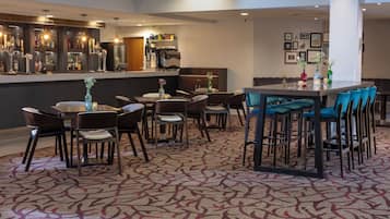 Un hall de hotel con zona de bar, distribución de asientos y alfombra estampada.