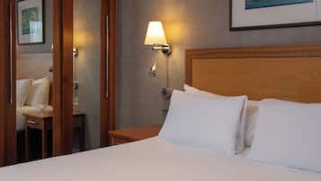 A hotel room with a neatly made bed, a bedside table with a lamp, and a painting on the wall.