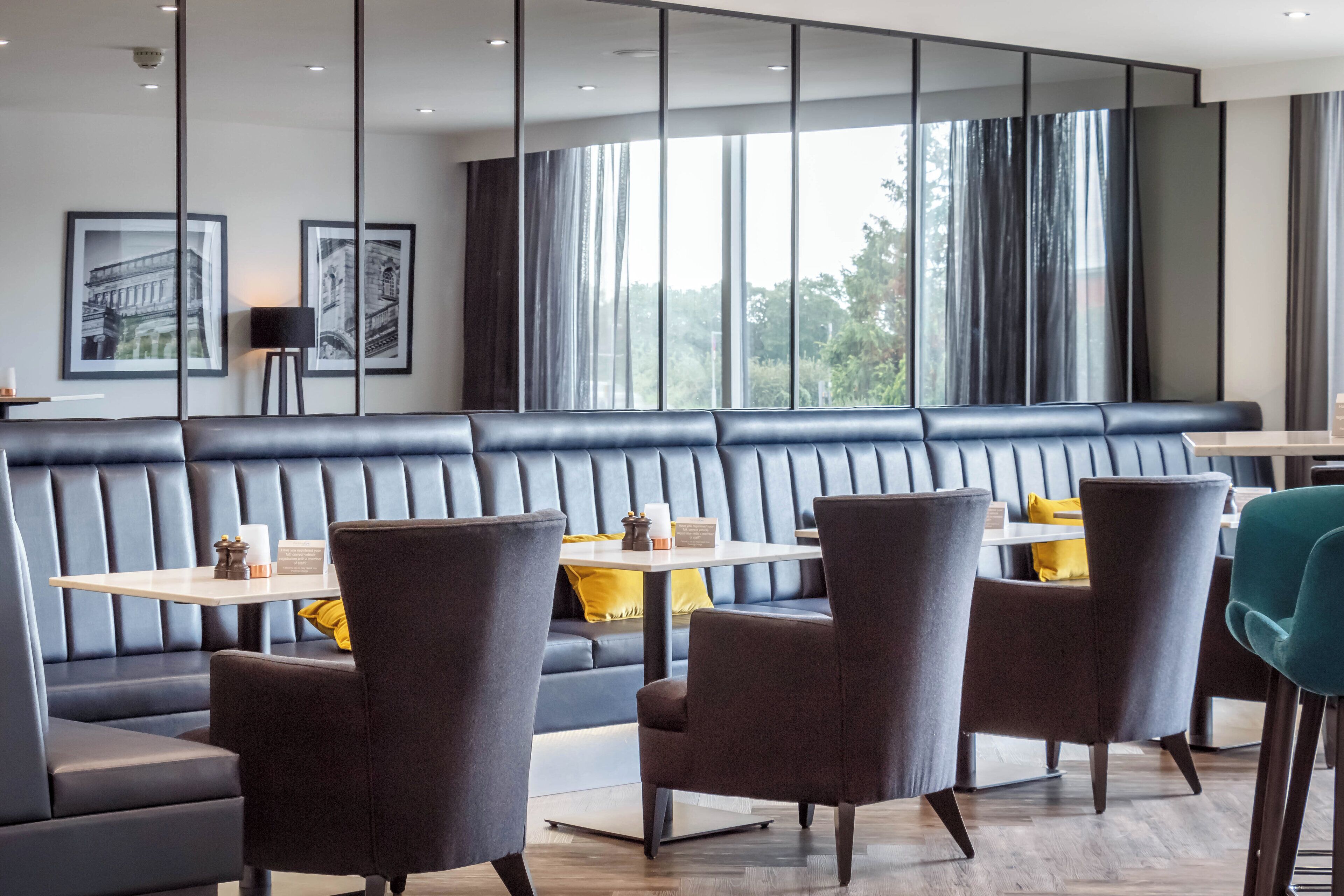 A modern dining area with a black leather booth seating, grey chairs, and a wooden table.