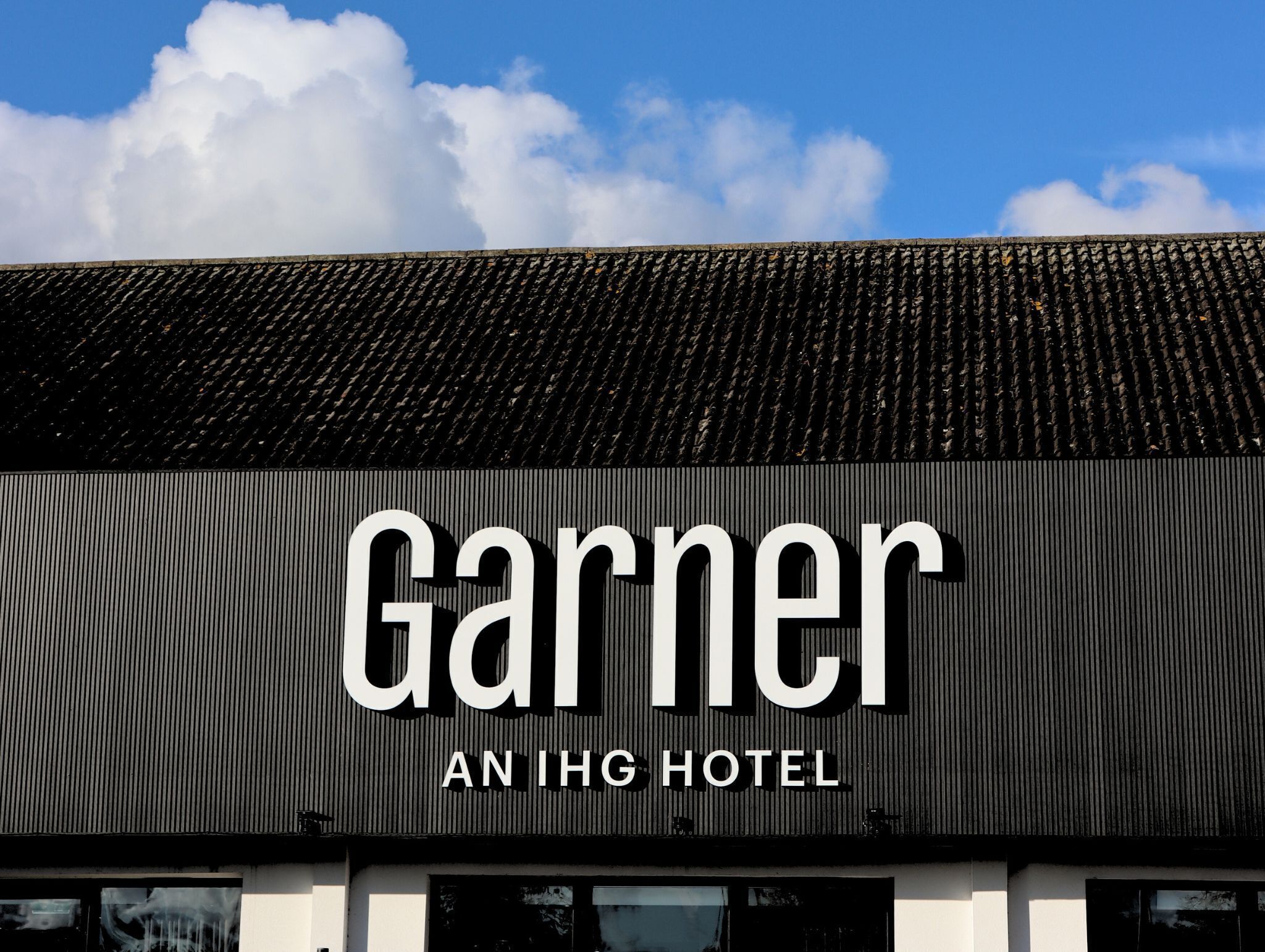 Exterior del Garner An IHG Hotel, con techo de metal corrugado y cielo despejado.
