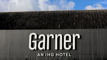 Das äußere Erscheinungsbild des Garner An IHG Hotel mit Wellblechdach und blauem Himmel.