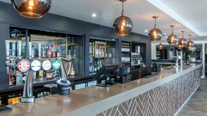Un espace bar doté de plusieurs tireuses à bière, d’une caisse enregistreuse et d’étagères remplies de bouteilles d’alcool.