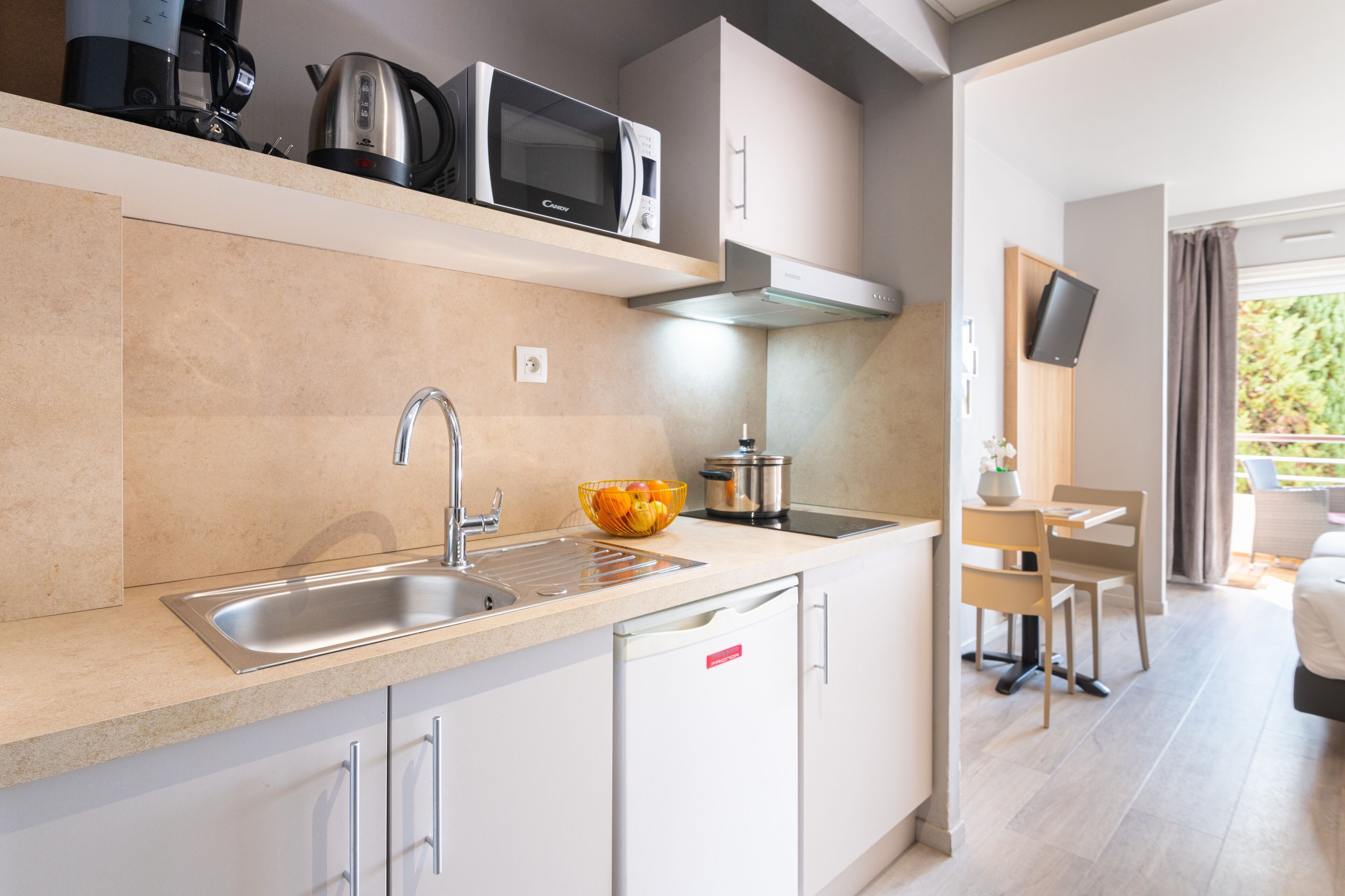 Een moderne keuken met een inbouwmagnetron, waterkoker en waterkoker op het aanrecht.