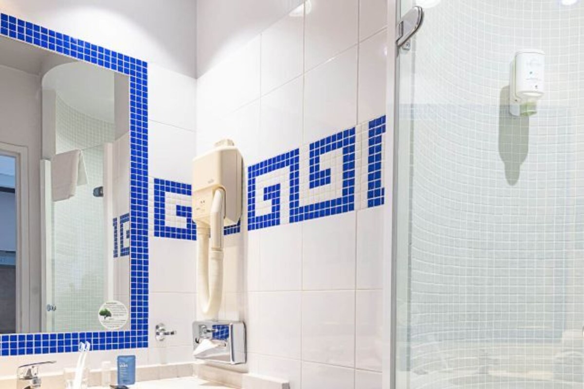 A bathroom with a mirror, sink, and shower.
