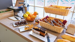 Una mesa de buffet con diversas opciones de comida, como frutas, pan y postres.