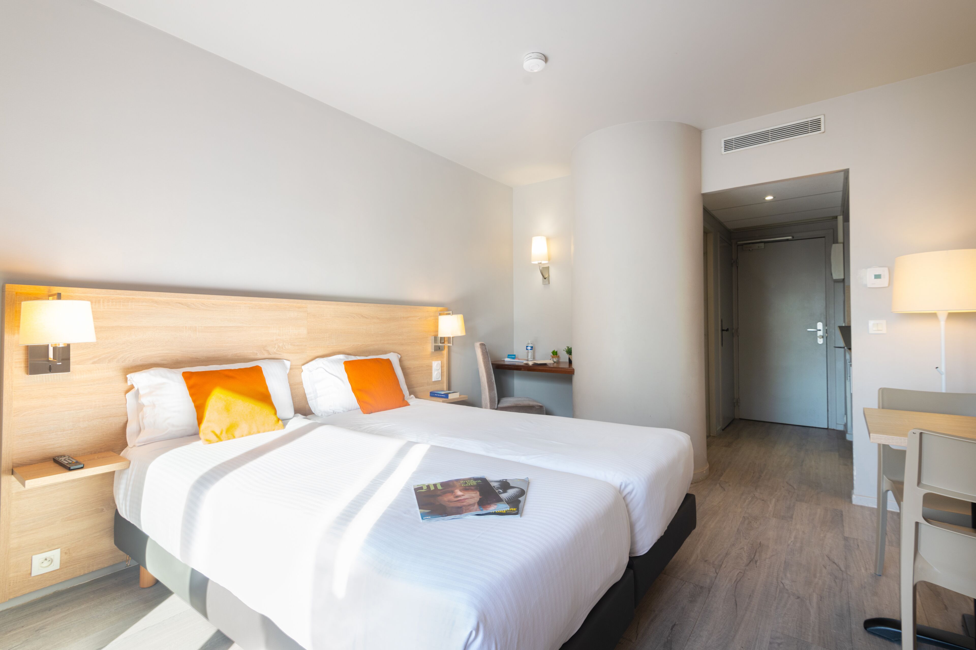 A hotel room with a large bed, bedside tables, a desk, and a chair.