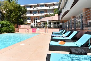 A pool area with lounge chairs and a building in the background. - Zenitude Hôtel-Résidences Le Cannet (Le Cannet)
