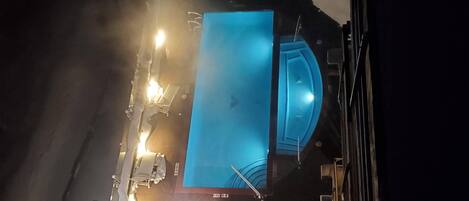 A swimming pool with a blue interior, surrounded by a deck with seating.