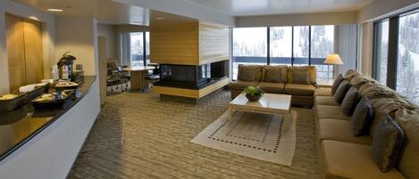 A modern living room with a fireplace, a sofa, a coffee table, and a dining area with a buffet.