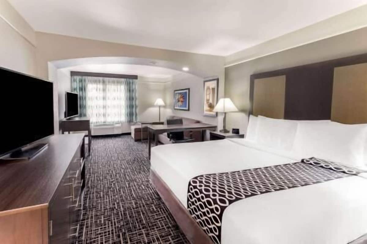Une chambre d’hôtel avec un grand lit, un bureau, une télévision et une vue sur la ville.