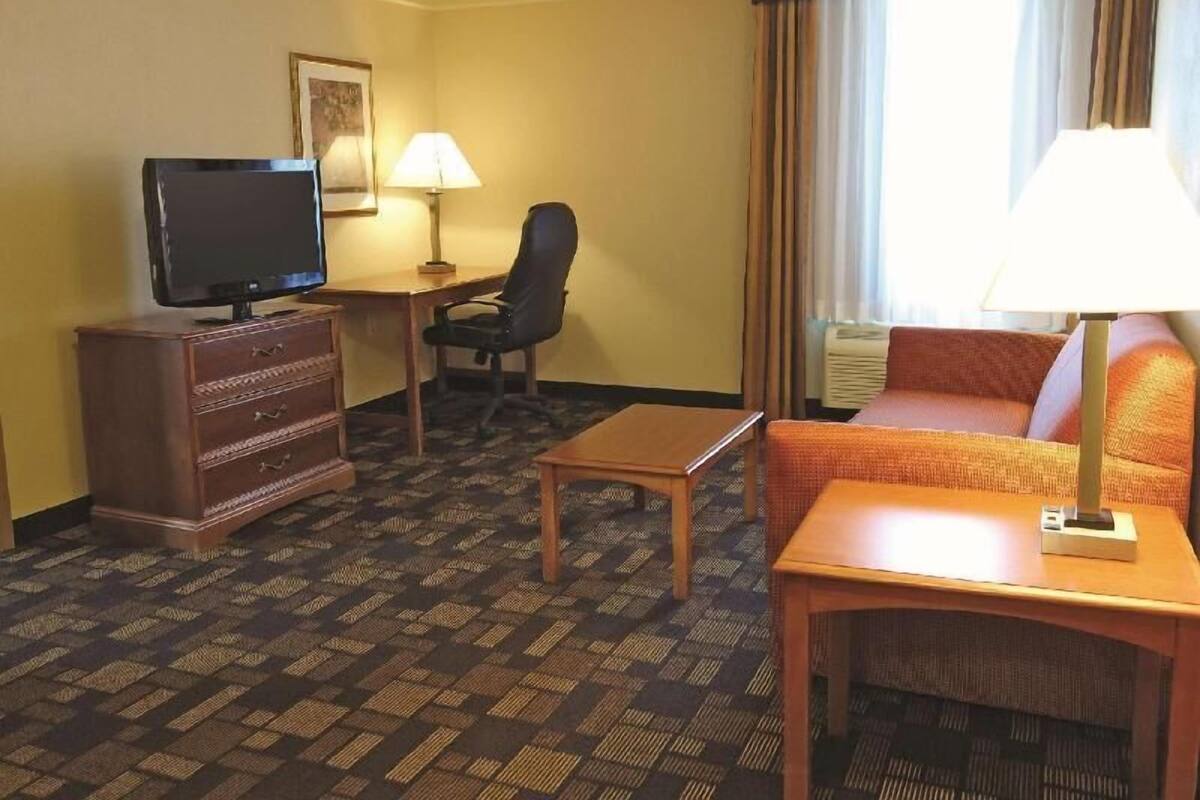 Une chambre d’hôtel équipée d’une télévision à écran plat, d’un bureau, d’une chaise, d’un canapé et d’une lampe.