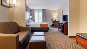 A hotel room with a bed, a sofa, a TV, a desk, and a lamp. - Comfort Suites South Haven near I-96 (South Haven)