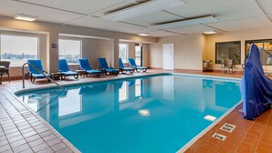 An indoor swimming pool with blue chairs and a tiled floor. - Comfort Suites South Haven near I-96 (South Haven)