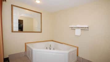 Un baño con una bañera grande, un espejo con marco dorado y un perchero para toallas.
