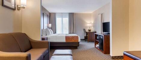 A hotel room with a bed, a sofa, a TV, and a desk.