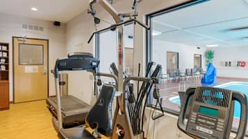 Un gimnasio con equipo de cardio, piscina y una puerta con un letrero.
