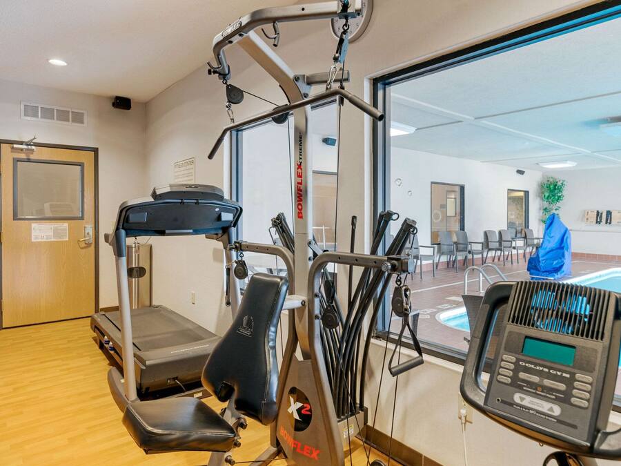 Un gimnasio con equipo de cardio, piscina y una puerta con un letrero.