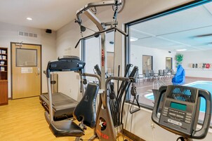 Un gimnasio con equipo de cardio, piscina y una puerta con un letrero.