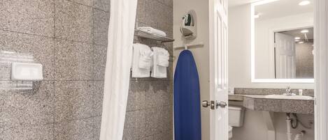 Een badkamer met een douche, een wastafel en een spiegel.
