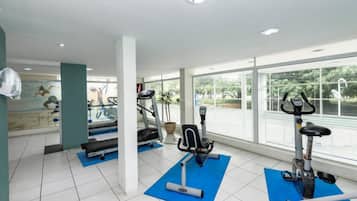 Una palestra con tapis roulant, ellittiche e tappetini per esercizi.