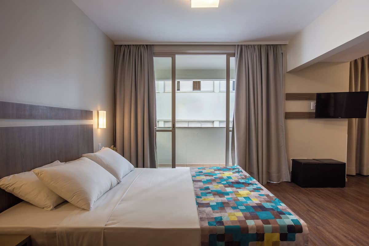 Une chambre d’hôtel avec un lit, une télévision et une vue sur le balcon extérieur.