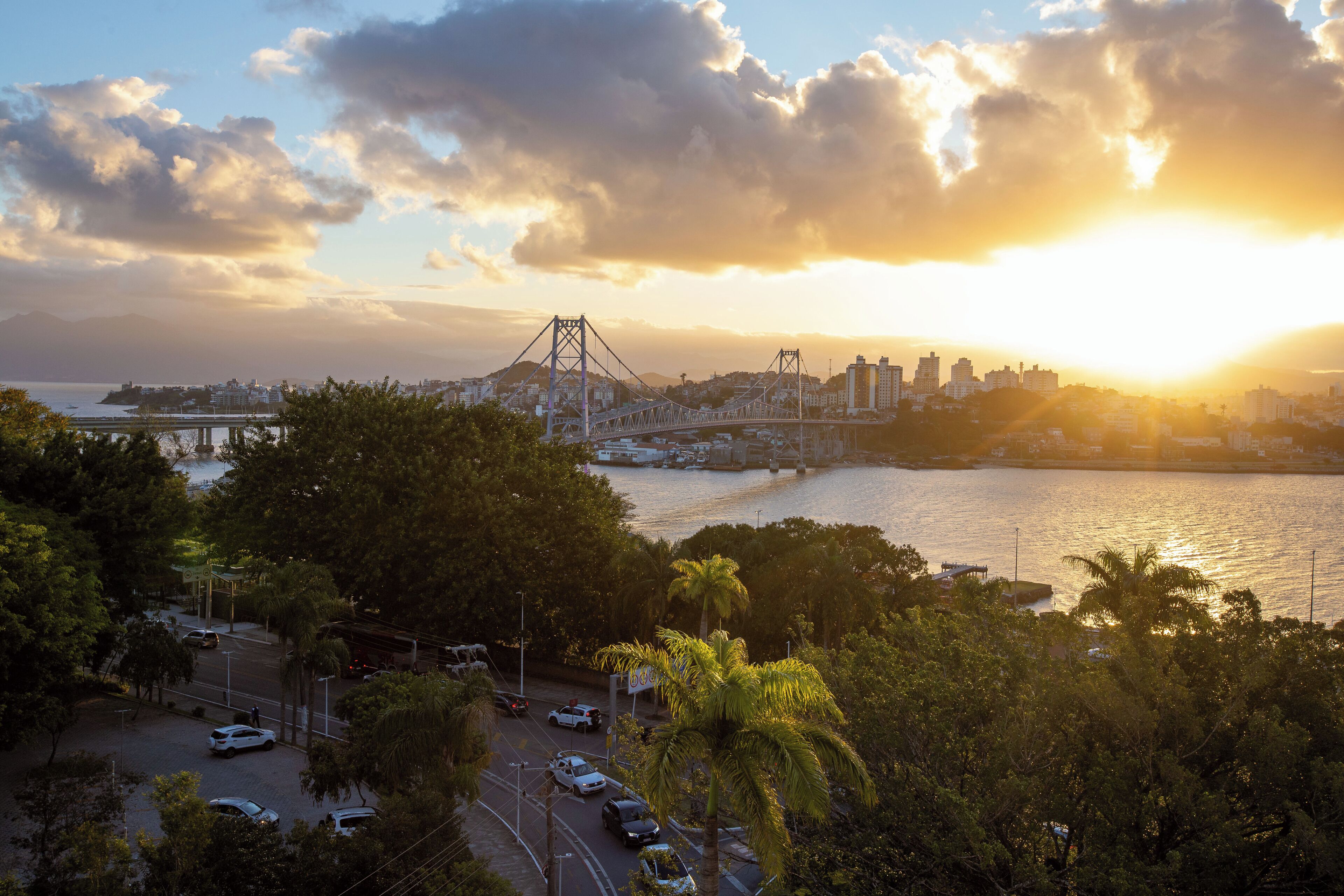 Une vue urbaine avec un pont, de l’eau et un coucher de soleil.