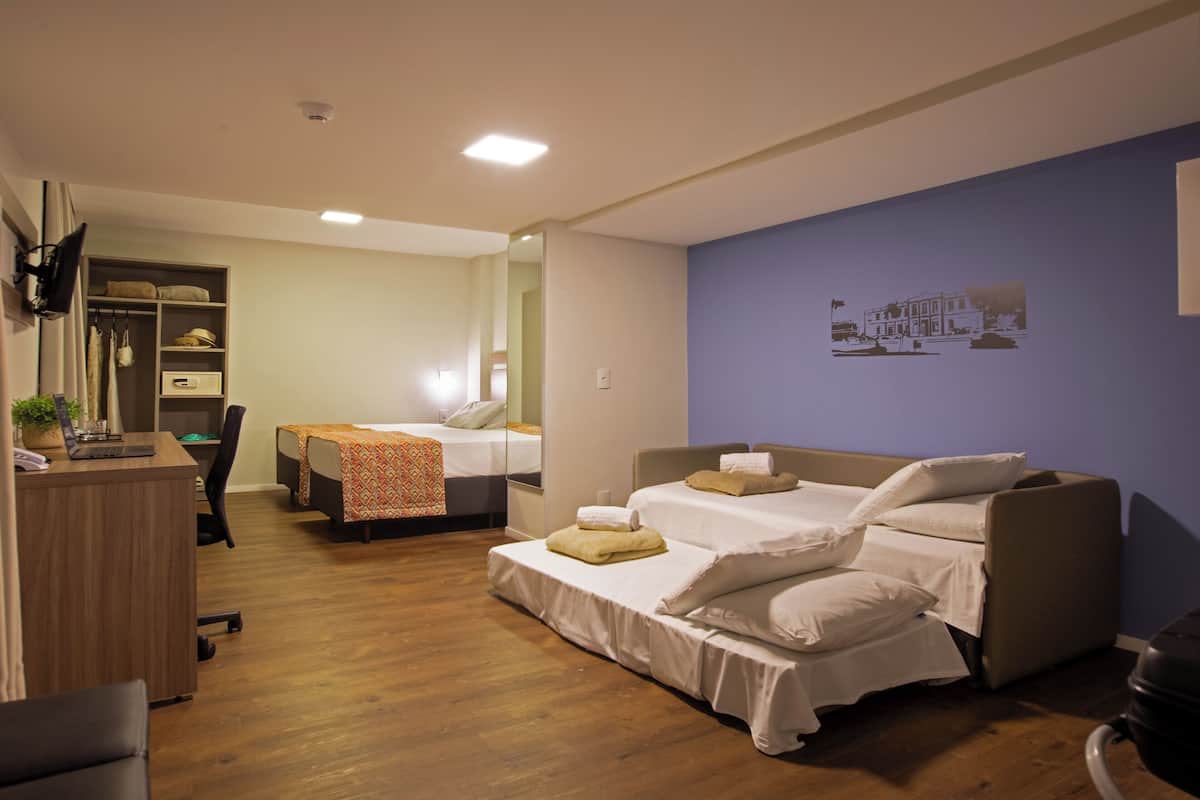 A hotel room with two beds, a desk, and a wardrobe.